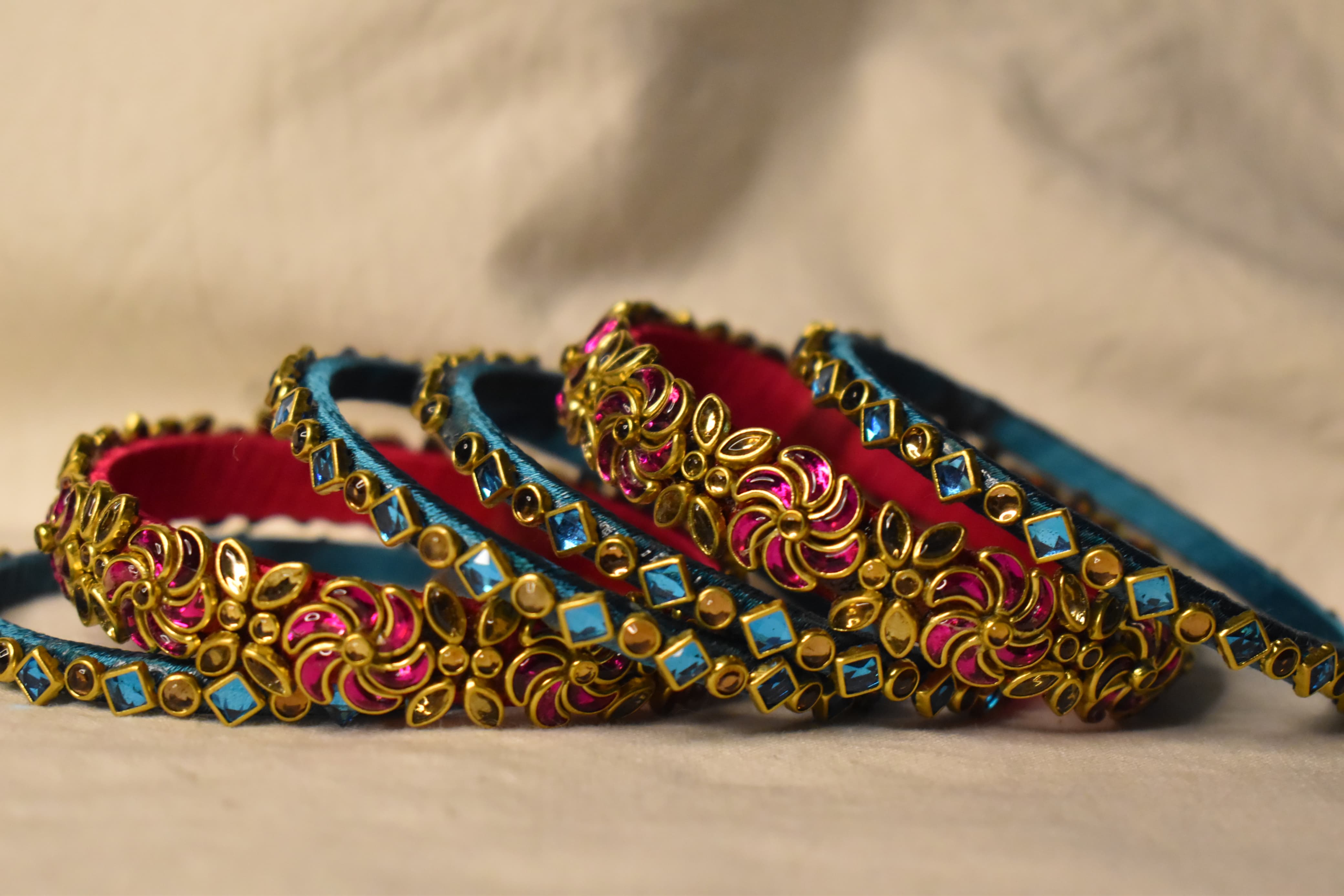 Teal blue and pink floral silk thread bangles with gold stone work by Neevijas