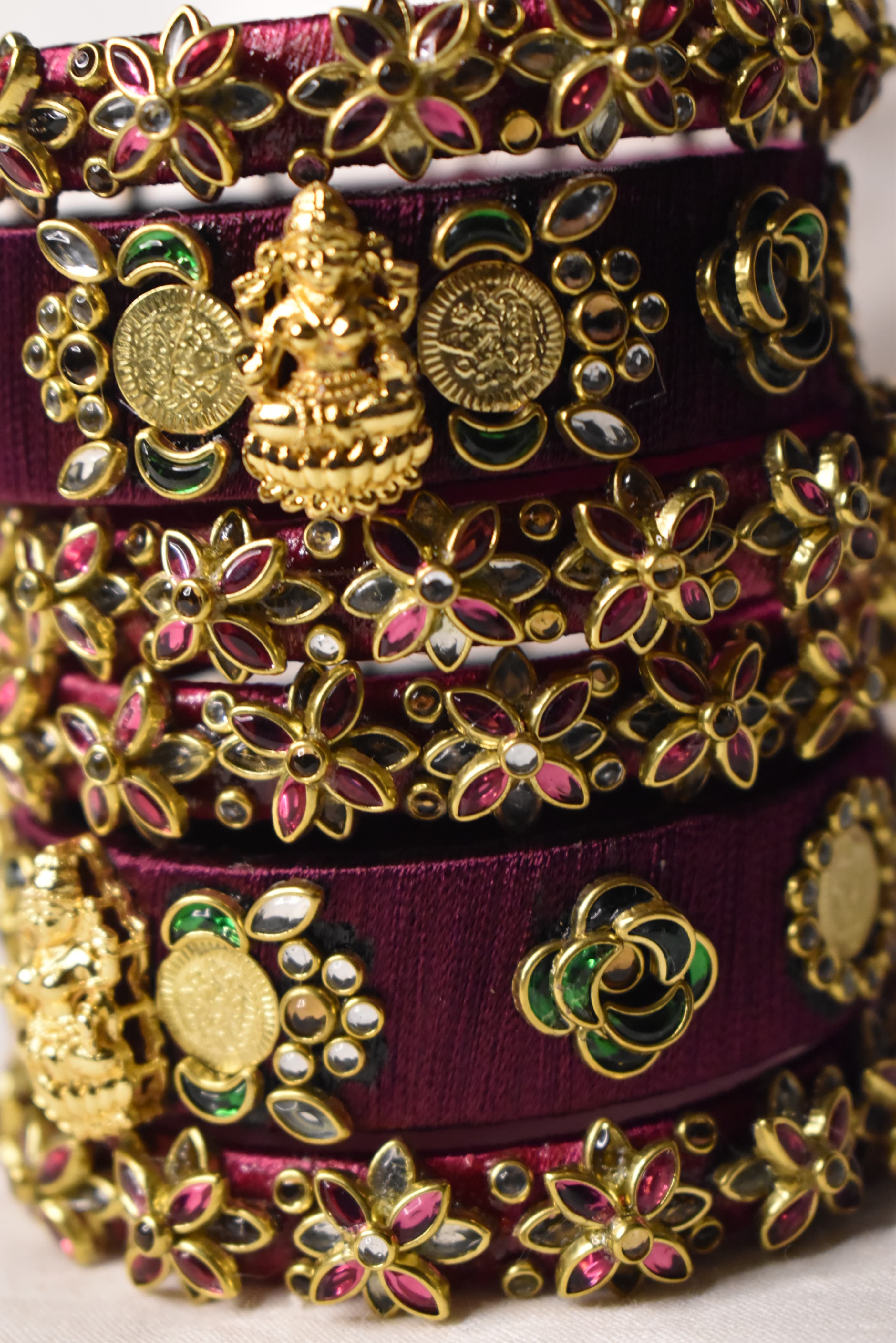 Detailed maroon bridal bangle hand finishing with gold charm work by Neevijas